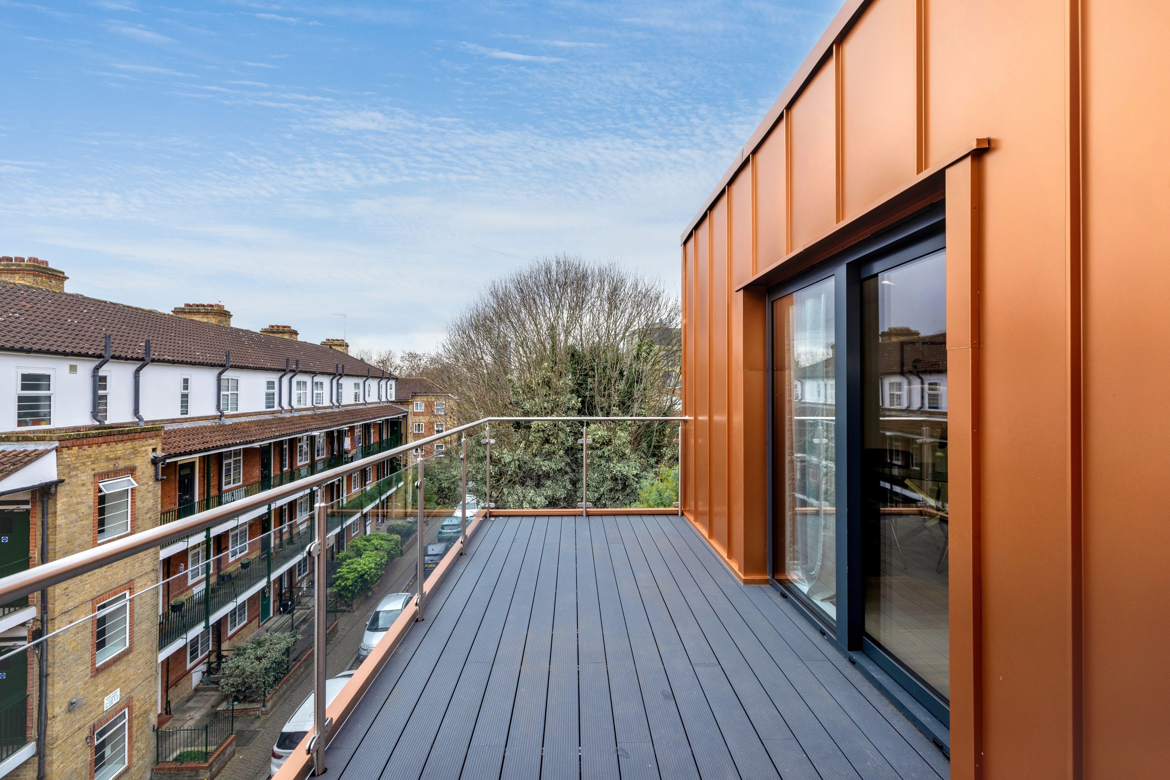 Un balcon d’habitation offrant une vue sur les maisons voisines et un arbre.