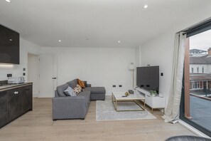 Ein modernes Wohnzimmer mit einem grauen Sofa, einem Couchtisch und einem Flachbildfernseher.