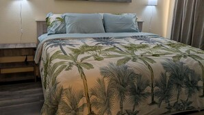 Ein Schlafzimmer mit einem Bett, einem Deckenventilator, einem Gemälde eines Piers und zwei Wandlampen.