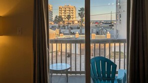 Ein Balkon mit Tisch und Stühlen, Blick auf ein Gebäude mit der Aufschrift 'WYNDHAM' und einem wolkenlosen Himmel.