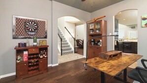 A spacious living area with a wooden coffee table, a dartboard, and a cabinet with bottles. - Family Home - Private Pool - Office - Pet Friendly (Fort Worth)