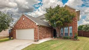 A two-story brick house with a white garage door, a front yard with grass and a tree, and a cloudy sky. - Family Home - Private Pool - Office - Pet Friendly (Fort Worth)