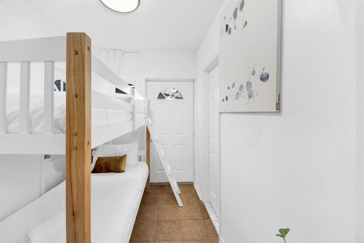 A narrow hallway with a bunk bed on the left and a door at the end.