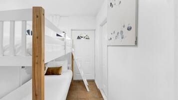 A narrow hallway with a bunk bed on the left and a door at the end.