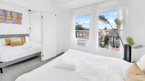 A modern bedroom with a bed, a door, and a window with curtains.