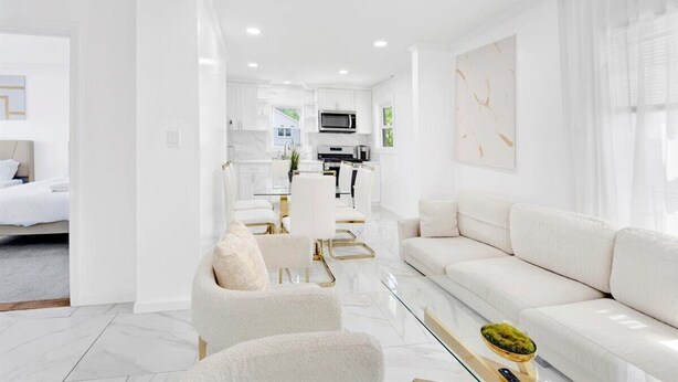 A modern living room with a sofa, armchairs, and a glass coffee table.