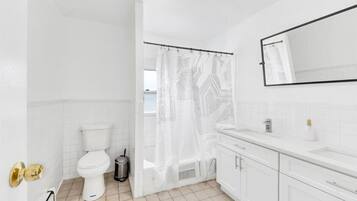 Un baño con inodoro, cortina de ducha, lavabo y espejo.