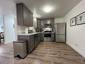 A modern kitchen with stainless steel appliances, wooden cabinets, and a tiled floor. - Extended Ski/Work/Visit secluded Cul-da-sac cutie (Salt Lake City)