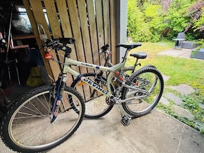 A mountain bike parked outside a wooden structure with a garden in the background. - Cozy Private 2BR Garden Suite in Central Vancouver (Vancouver)