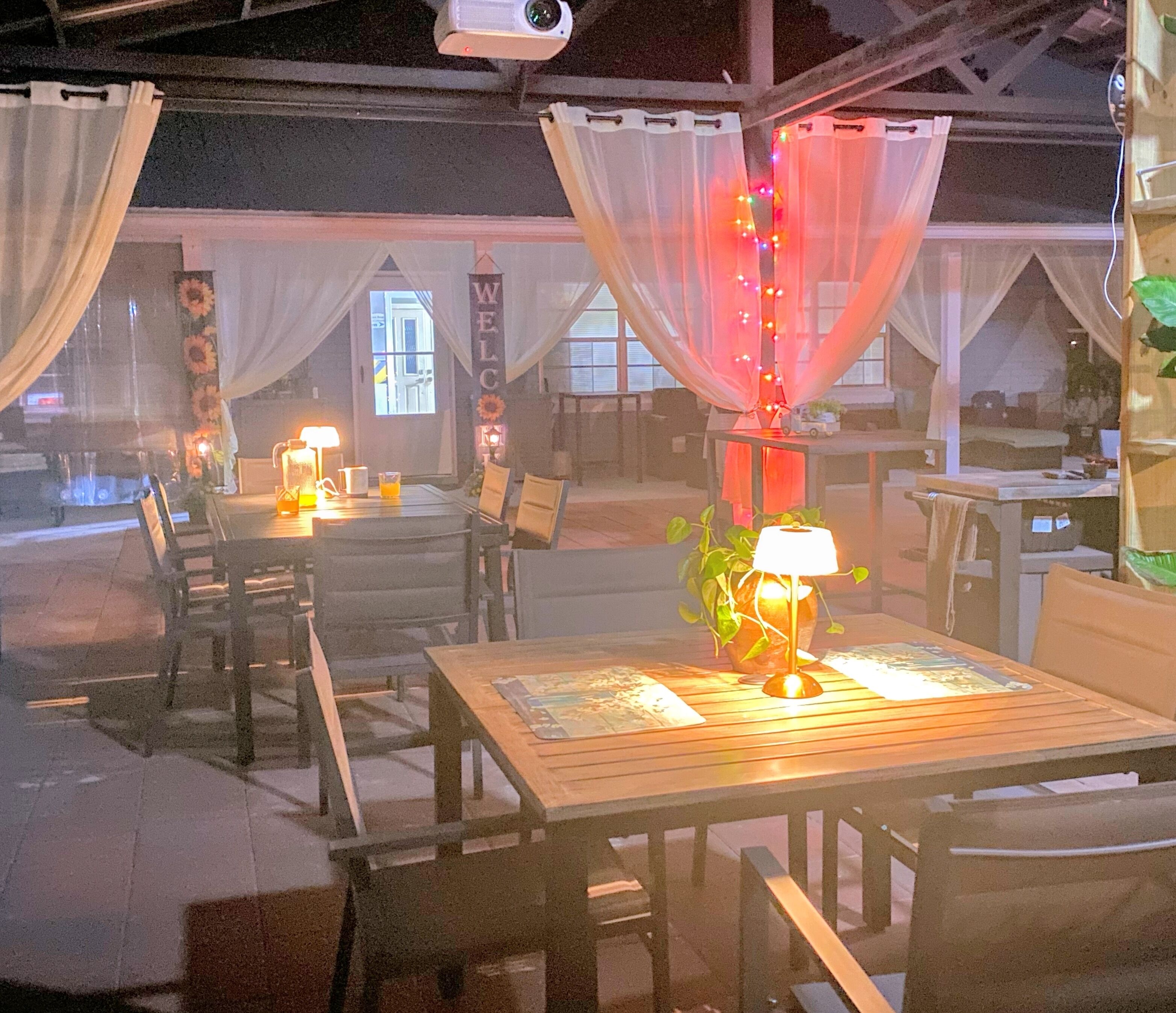 An outdoor dining area with tables and chairs, a lamp, and a sign that reads "WELCOME".
