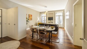 Un salon moderne comprenant un coin repas, un plancher en bois et une grande fenêtre laissant entrer la lumière naturelle.