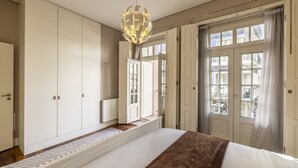 Une chambre dotée d’un grand lit, d’une armoire, d’une fenêtre avec des rideaux et d’un luminaire sphérique original.