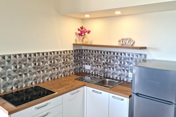 A modern kitchen with a geometric backsplash, a built-in stove, a sink, and a refrigerator.