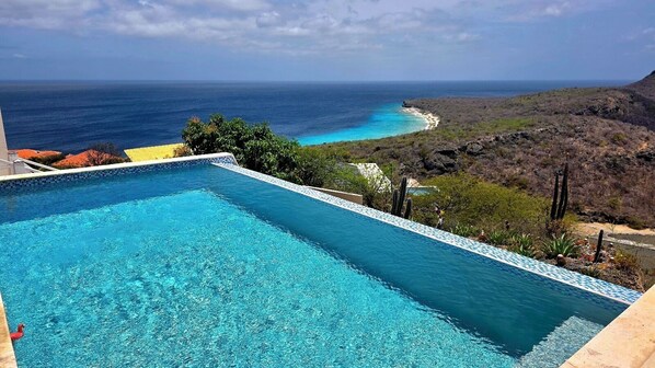 Une piscine avec vue sur l’océan et une plage.