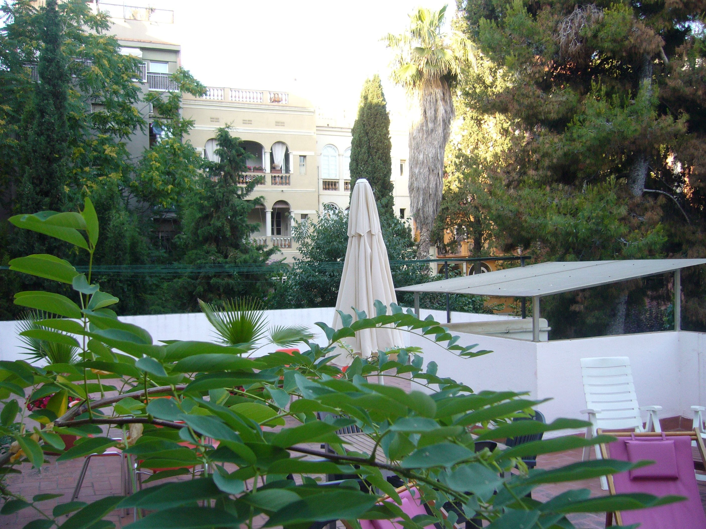 Une terrasse sur le toit avec un parasol blanc, une chaise blanche et une serviette rose.