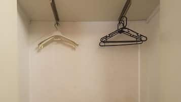 A small storage closet with a microwave, a hanging clothes rack, and a step leading to a lower level.
