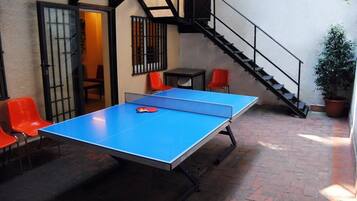 A ping pong table in an outdoor area with red chairs and a staircase.