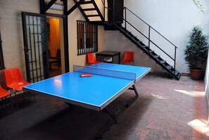 A ping pong table in an outdoor area with red chairs and a staircase. - Hostel Albergue Studio (Barcelona)