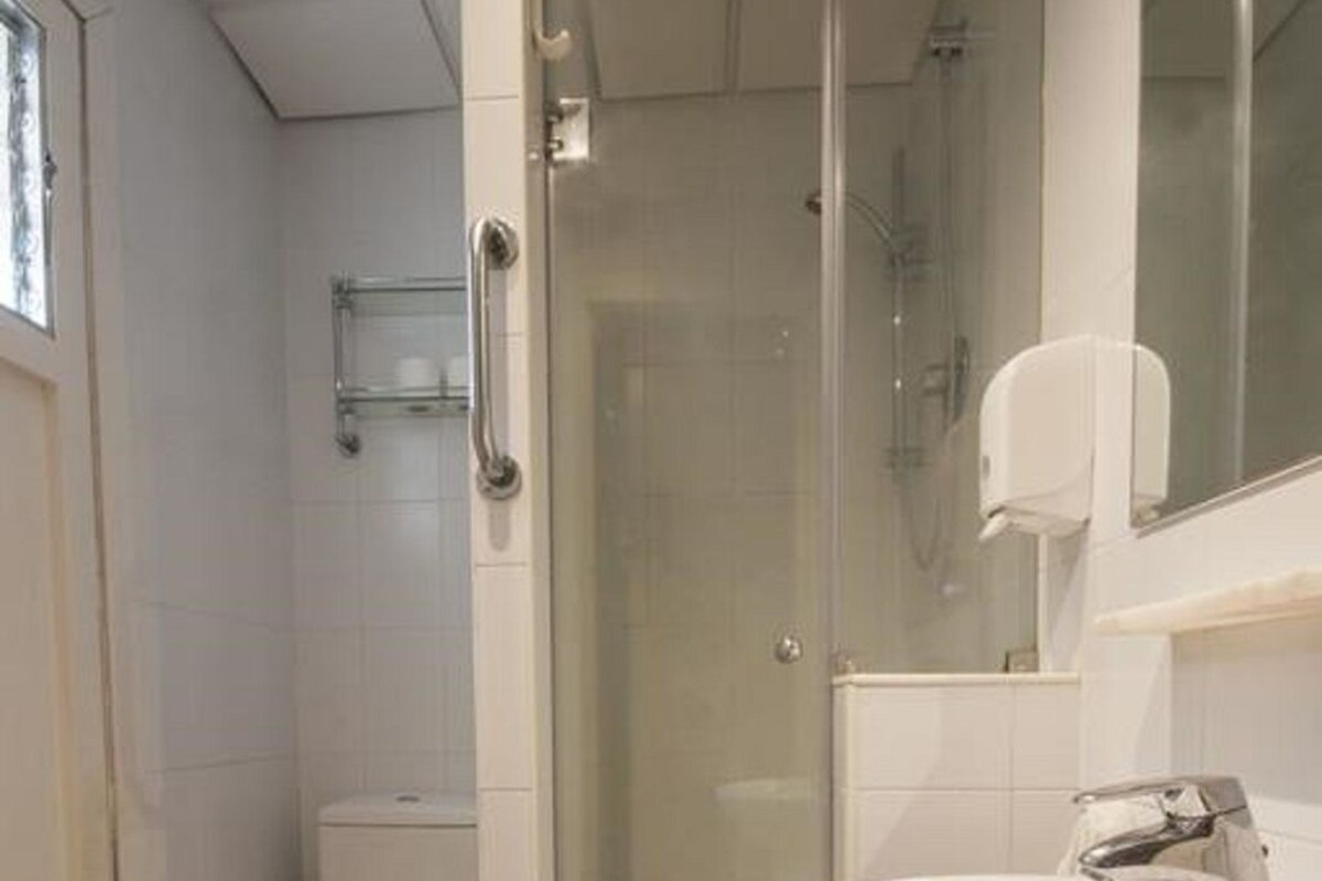 A bathroom with a toilet, a glass-enclosed shower, and a sink with a mirror.