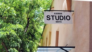 A sign for 'Albergue Studio Hostel' with a view of trees and a building facade. - Hostel Albergue Studio (Barcelona)
