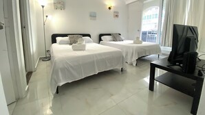 Ein Hotelzimmer mit zwei Betten, einem Fernseher und einem Balkon mit Vorhängen.