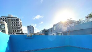 Ein Dachpool mit klarem, blauem Wasser, umgeben von einer blauen Wand und einer gefliesten Kante.