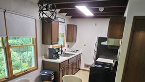 Cocina compacta con comedor, muebles de madera, estufa integrada y ventana con vistas a zonas verdes.