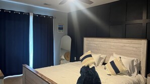 Ein Schlafzimmer mit einem hölzernen Bett, weißer Bettwäsche und einem Deckenventilator.