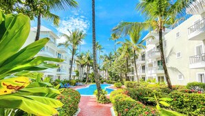 Ein Resort mit Schwimmbad, Palmen und einem roten Weg.