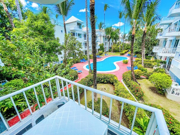 A resort with a swimming pool surrounded by lush greenery and palm trees. - DELUXE STUDIOS HOTEL POOL AND BEACH (Punta Cana)