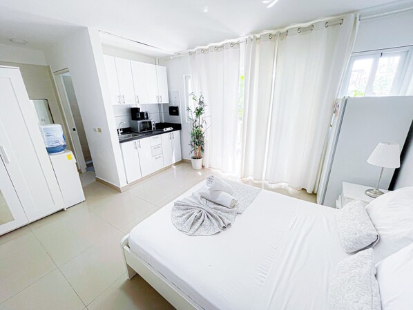 Quarto de hotel com cama, uma kitchenette pequena e banheiro.