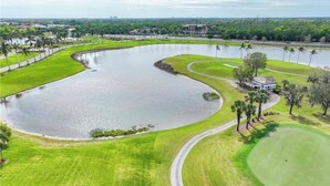 Un campo de golf con un estanque grande, césped cuidado y un club de campo.