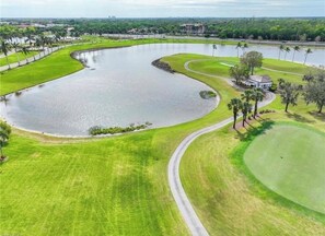 Ein Golfplatz mit einem großen Teich, gepflegtem Rasen und einem Clubhaus.