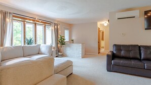 Un salón con un sofá beige, un sofá de cuero oscuro y una chimenea blanca.