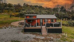 Une cabane en bois à deux étages, dotée d’une terrasse et entourée d’un paysage naturel.
