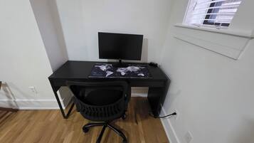 A small, neatly organized workspace with a black desk, a black chair, and a world map on the desk.