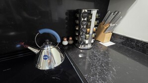 A kitchen counter with a kettle, a spice rack, and a knife block. - Quiet cheerful condo in the heart of OTR! (Cincinnati)