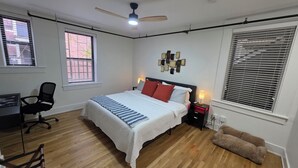 A bedroom with a bed, a desk, a chair, a ceiling fan, and a window with blinds. - Quiet cheerful condo in the heart of OTR! (Cincinnati)