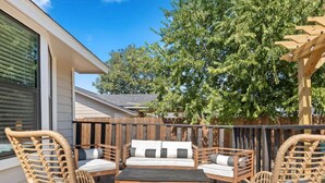 An outdoor patio with wicker furniture, a sofa, and a patterned rug. - Poolside Paradise Room Fire Pit Hot Tub (Round Rock)