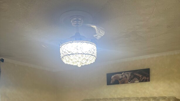 Une chambre à coucher avec une tête de lit capitonnée, un grand lit avec de nombreux oreillers, une couverture moelleuse, un tableau accroché au mur et un luminaire fixé au plafond.