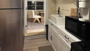Une cuisine de taille réduite, avec des meubles blancs, un réfrigérateur en acier inoxydable, un four à micro-ondes noir et une cuisinière.