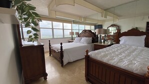 Une chambre avec deux lits, une grande fenêtre et une plante.