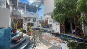 A courtyard with a staircase, potted plants, and a tiled floor. - PENGUIN HOSTEL (Puerto Ayora)