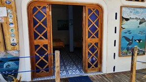 A wooden door with a blue glass panel, a tiled floor, and a painting of marine life on the wall. - PENGUIN HOSTEL (Puerto Ayora)