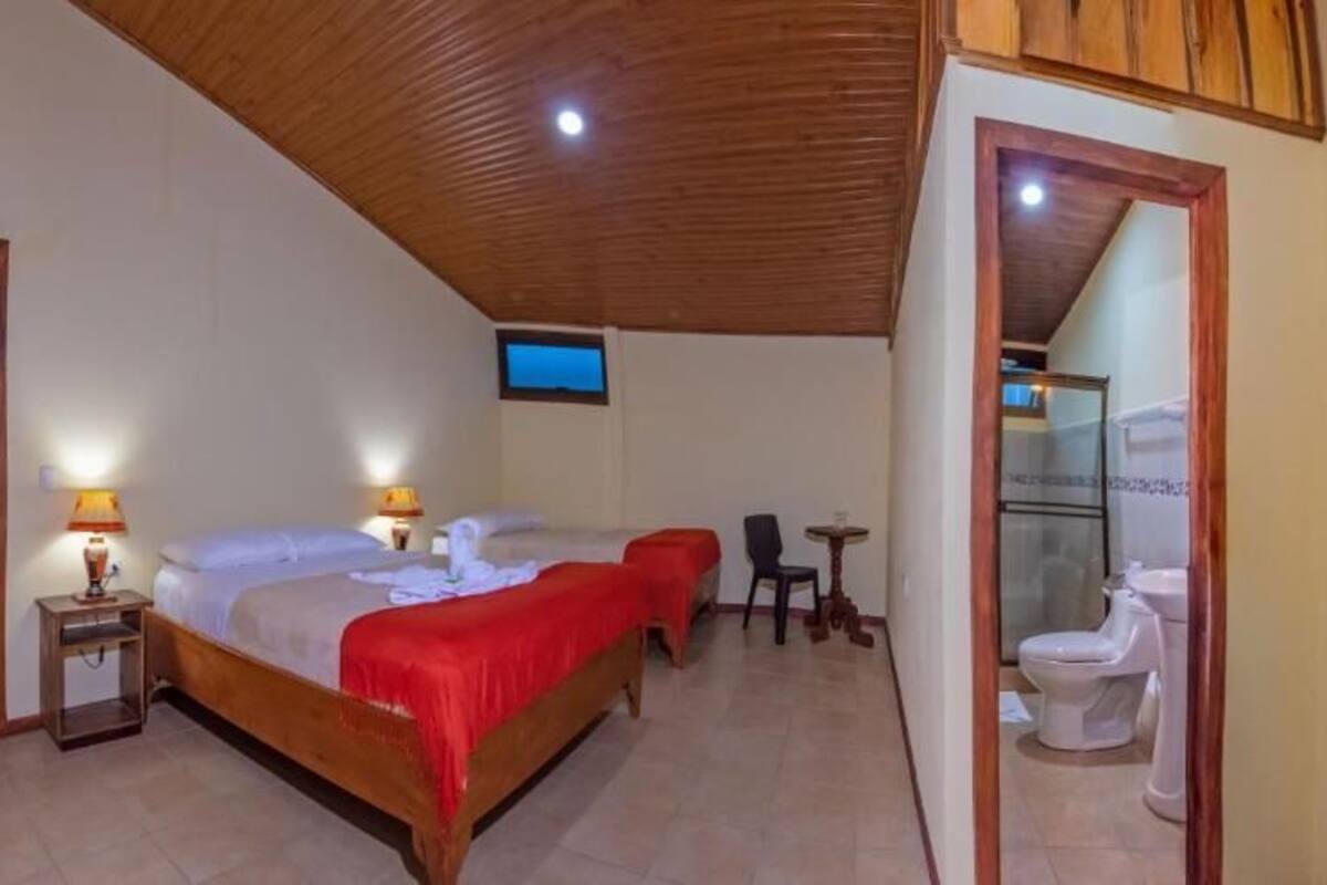 A bedroom with two beds, a TV, a small table, and a chair.