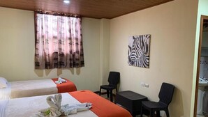 A hotel room with two beds, a zebra artwork on the wall, a small table, and a chair. - Casa Madonna Hotel (Monteverde)