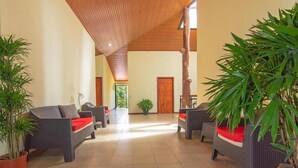 A spacious indoor area with wicker furniture, potted plants, and a wooden ceiling. - Casa Madonna Hotel (Monteverde)