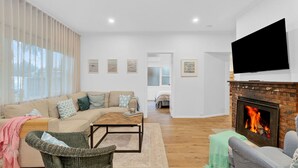 Una sala de estar con sofá, mesa de centro, chimenea, televisor y obras de arte en la pared.