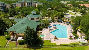 A hotel with a swimming pool, multiple buildings, and surrounding greenery. - Near Disney Cozy 3Bd Apartment at Caribe Cove (Kissimmee)
