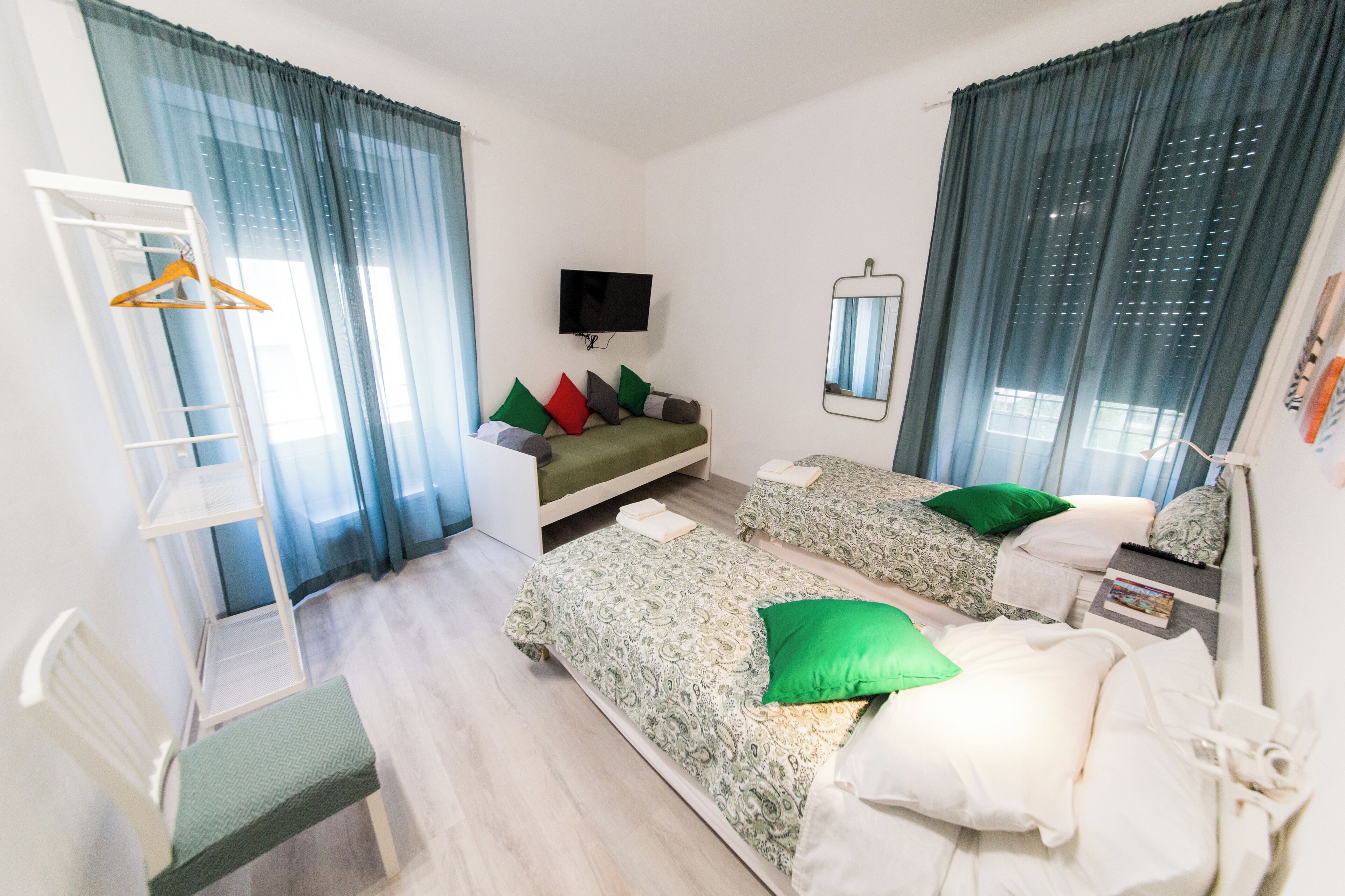 A hotel room with two beds, a TV, a mirror, and a wardrobe.